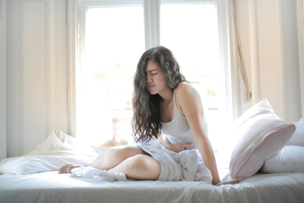 Woman crouched over in bed in pain