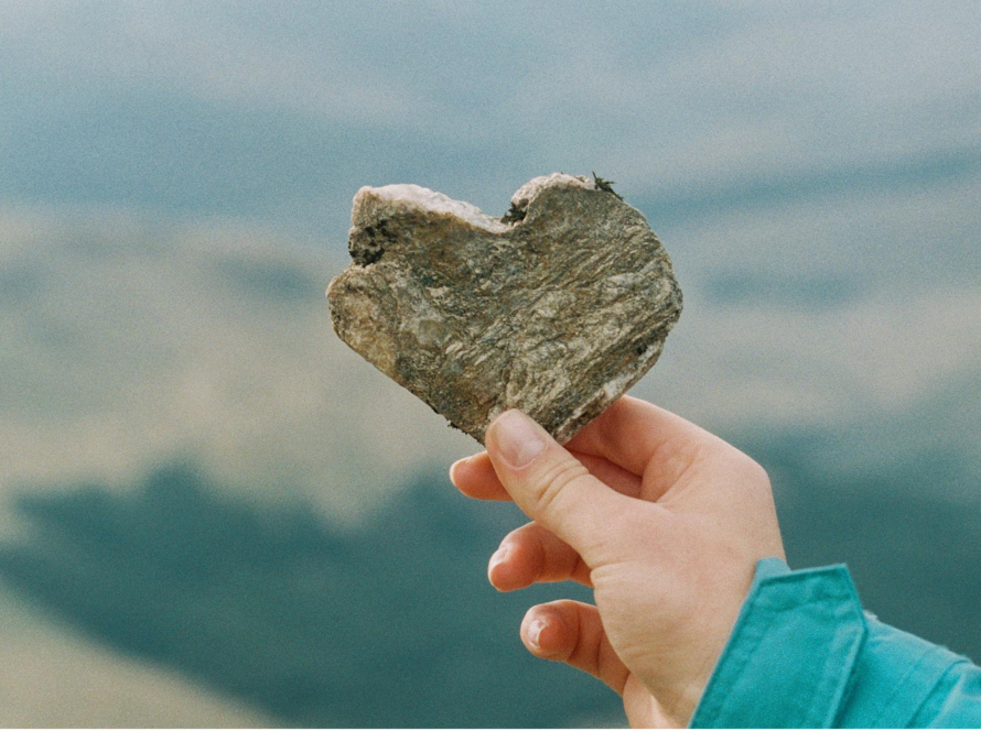 A hand holding a heart-shaped stone.